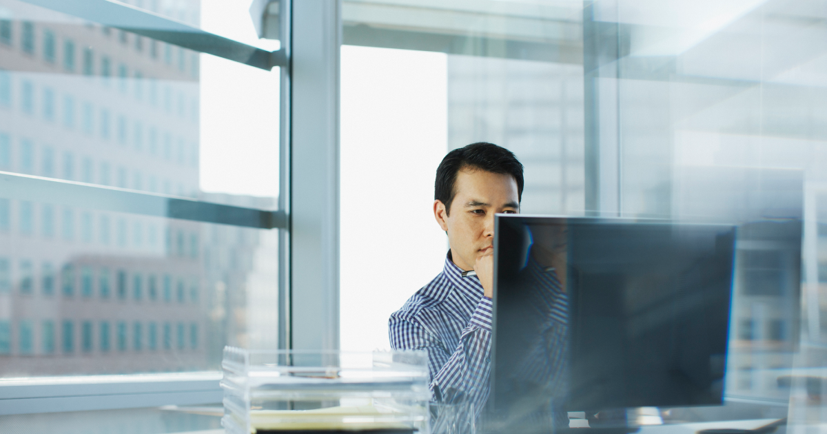 PCモニターを見ながら考え込む男性