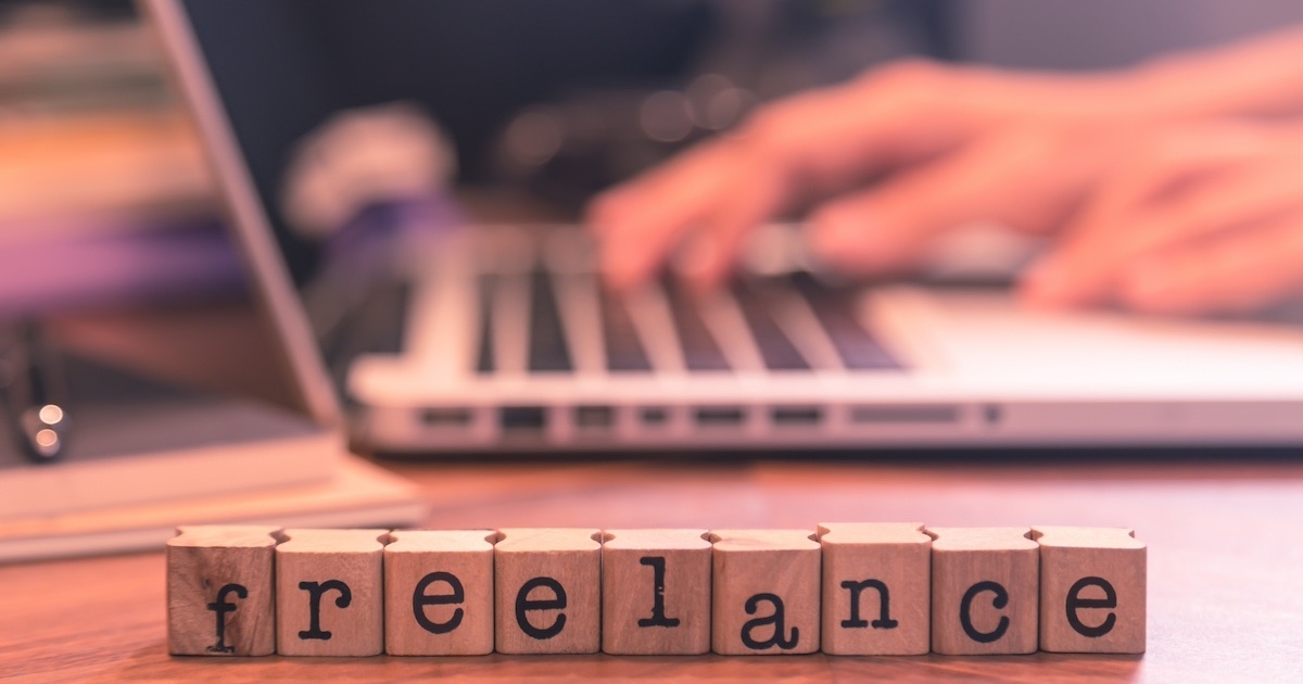 パソコンをする手元と「freelance」と書かれたブロック