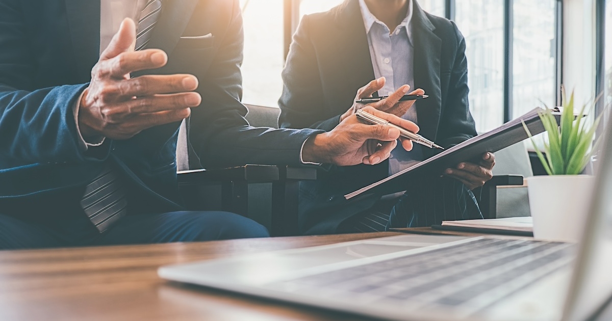 机にパソコンを置き話し合うビジネスマン