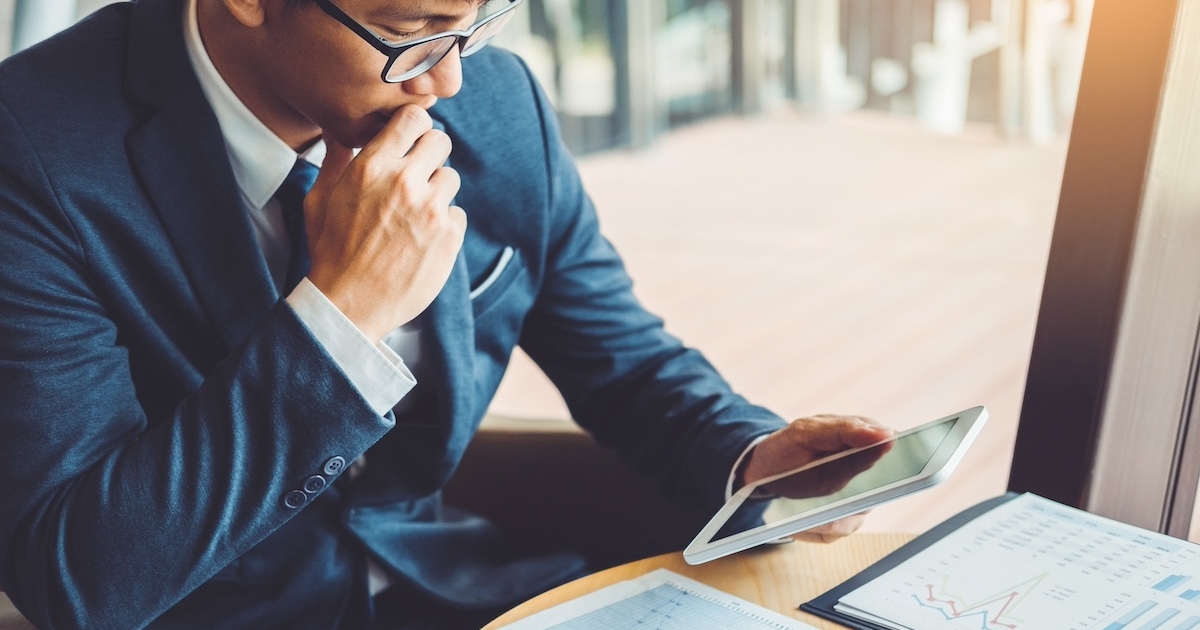タブレットを片手に考え込むビジネスマン