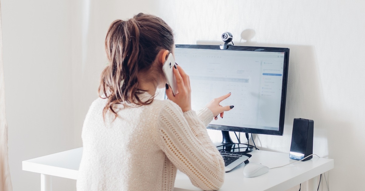 通話しながらパソコンモニターを指さしている女性
