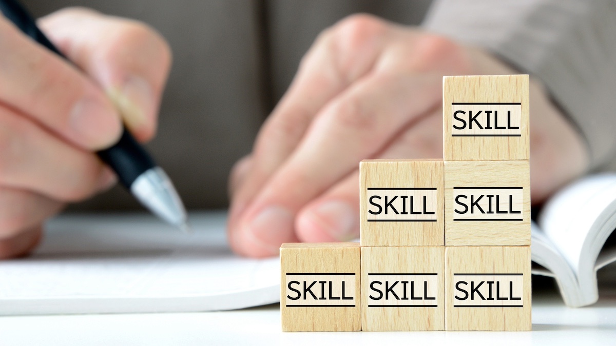 字を書く手元と「SKILL」と書かれたブロックが積まれている