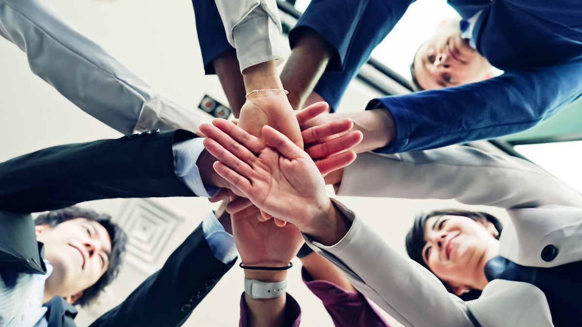 円陣を組み手を重ねている男女