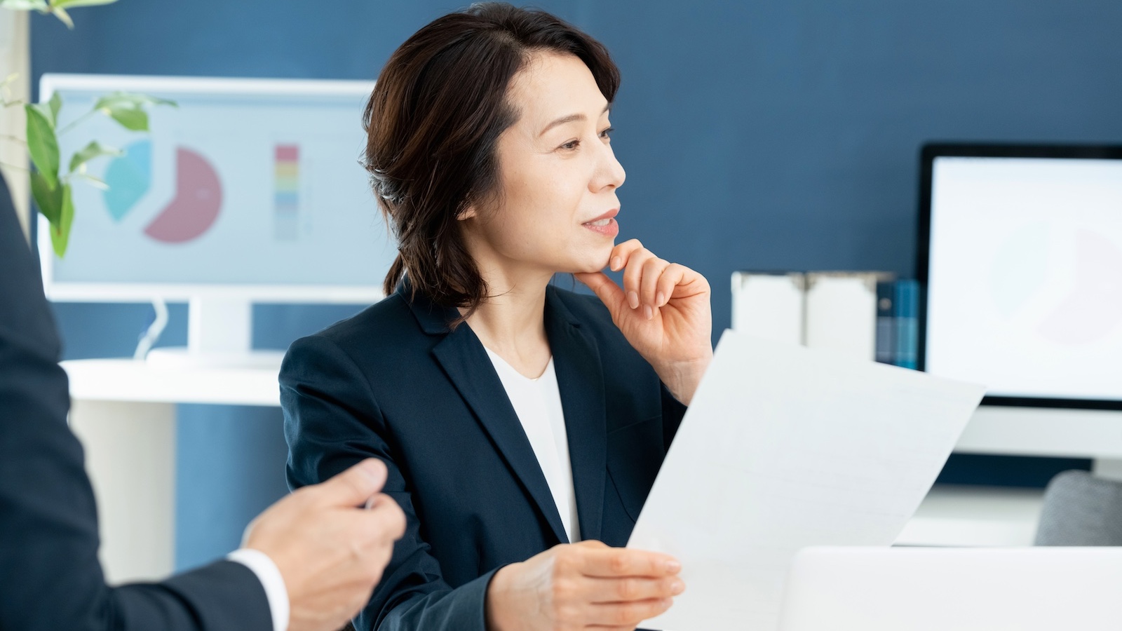 資料を持ち考えるビジネスパーソン