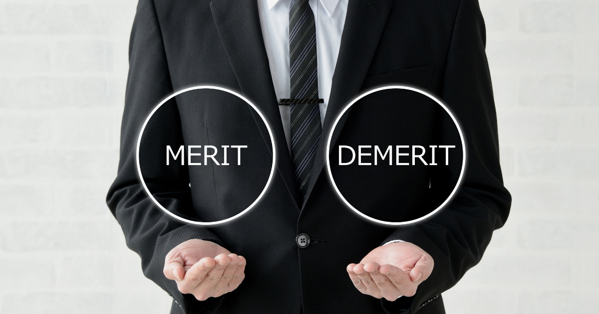「MERIT」と「DEMERIT」の文字を両手で示す男性