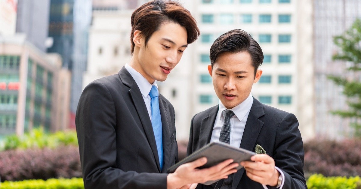 タブレットを手に話し合うビジネスマン2人