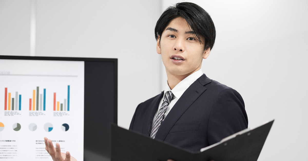 モニターに資料を映してプレゼンする男性