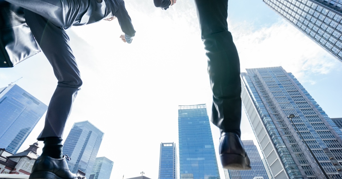 ビジネス街をジャンプする2人のビジネスパーソン