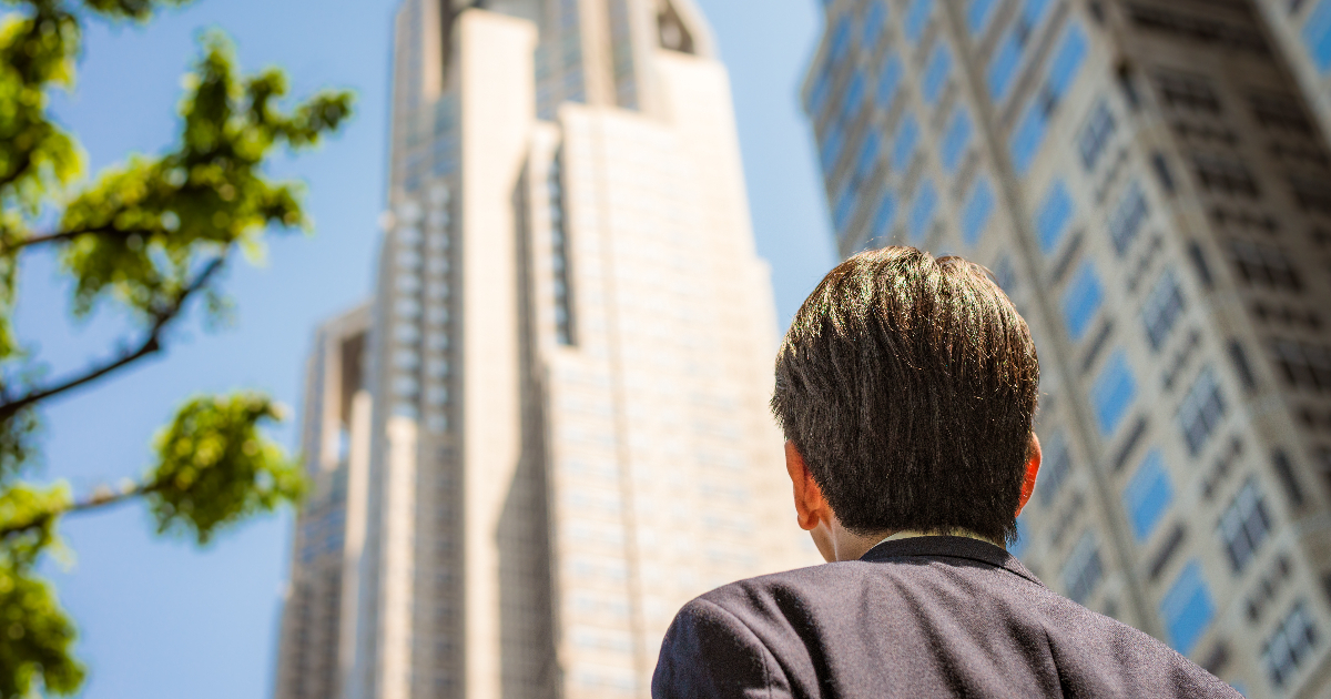 高層ビルを見上げる男性
