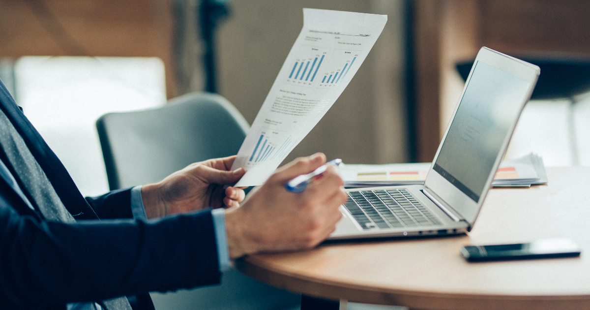 ノートパソコンの前で資料を確認している男性