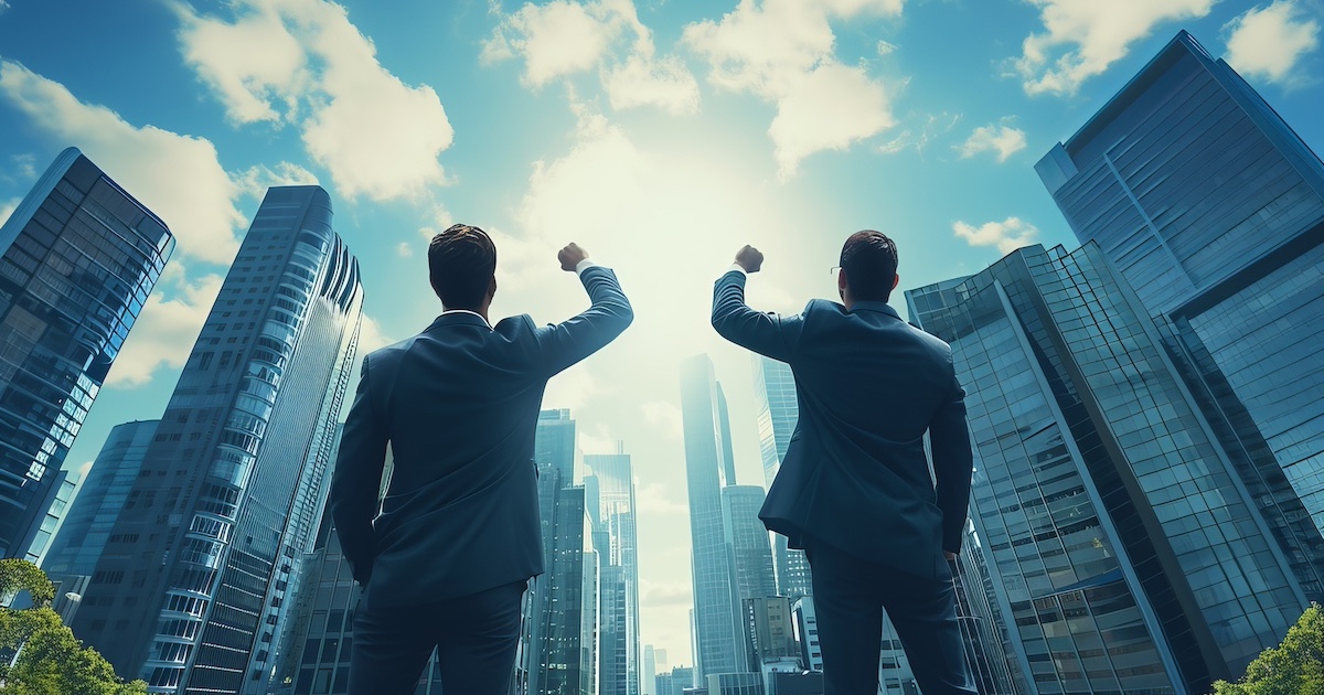 ビジネス街で空に向かって拳をあげるビジネスマン2人