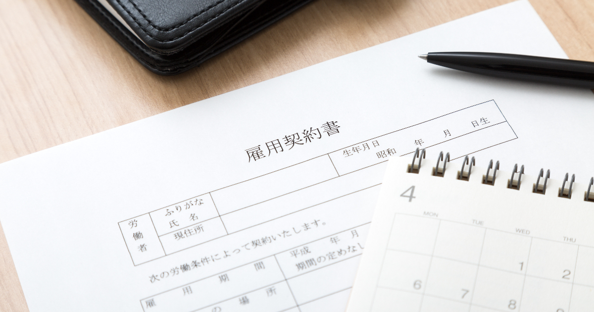 雇用契約書とカレンダー、その横に置かれたボールペン