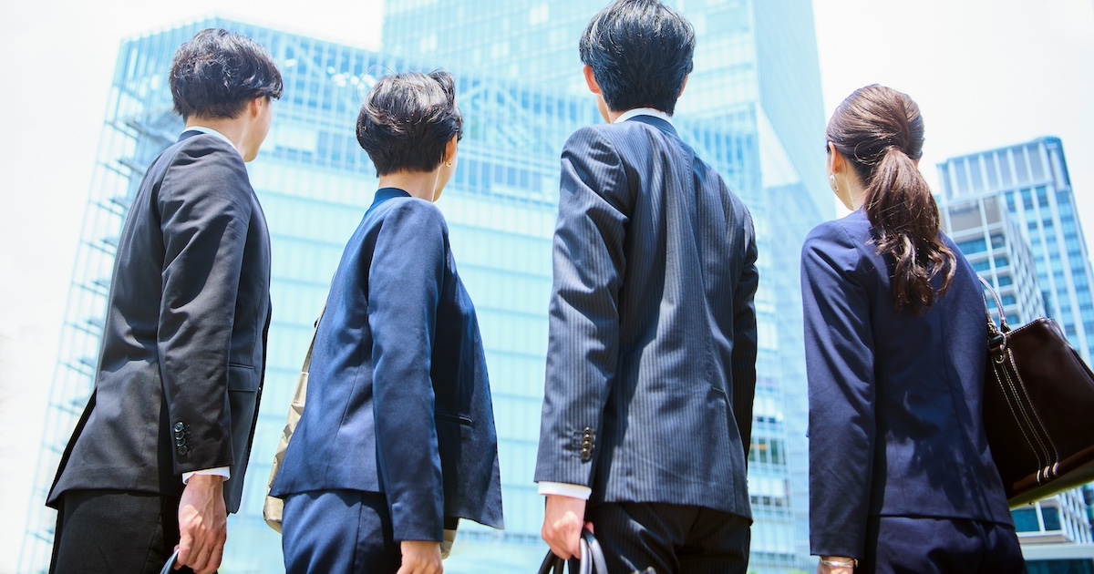 ビル街の中空を見つめるビジネスマン達の後ろ姿