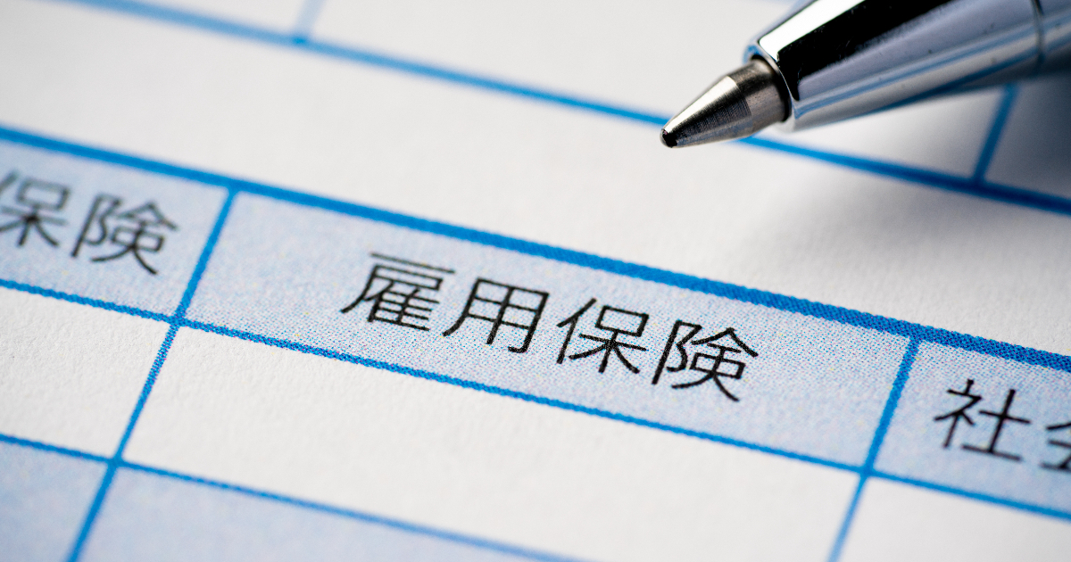 雇用保険と記載された給与明細とボールペン