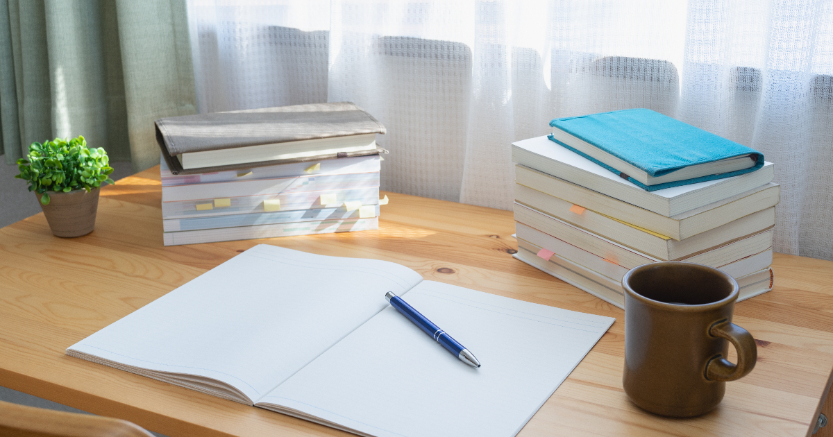 開いたノートと積みあげられた書籍