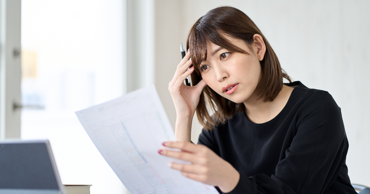 書類を見ながら悩む女性