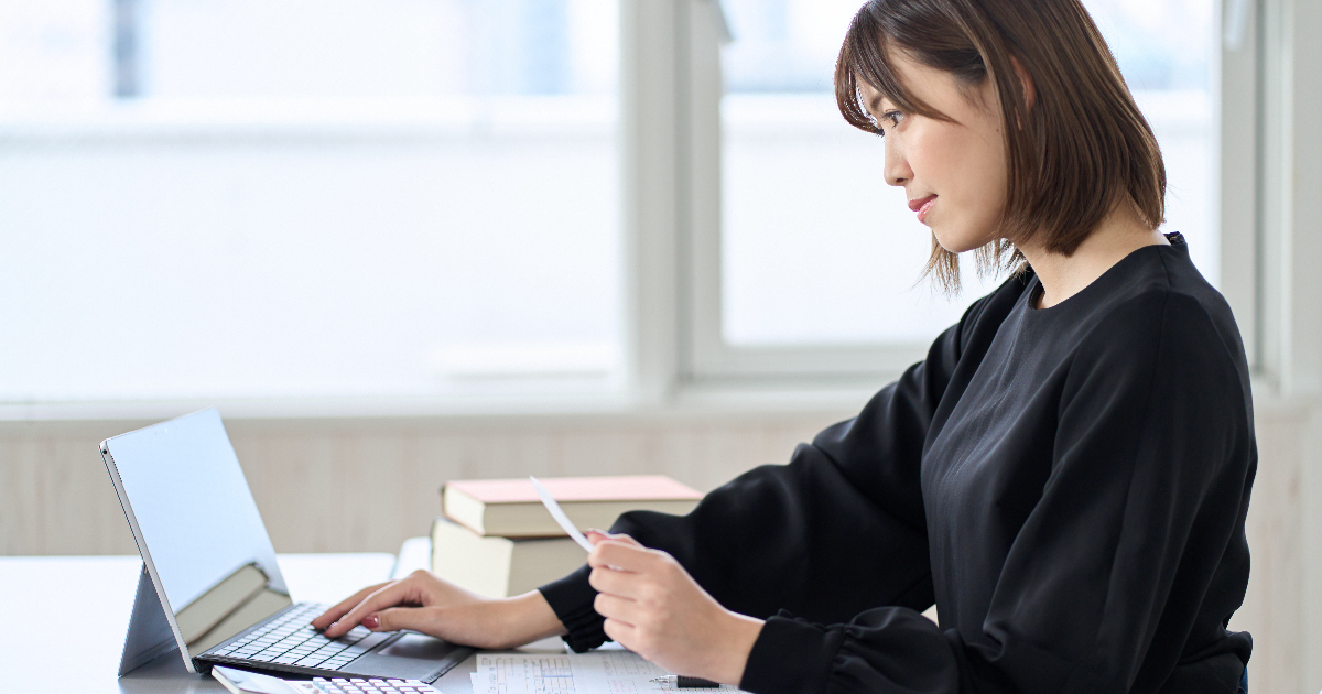 領収書を手に持ちパソコンに入力する女性