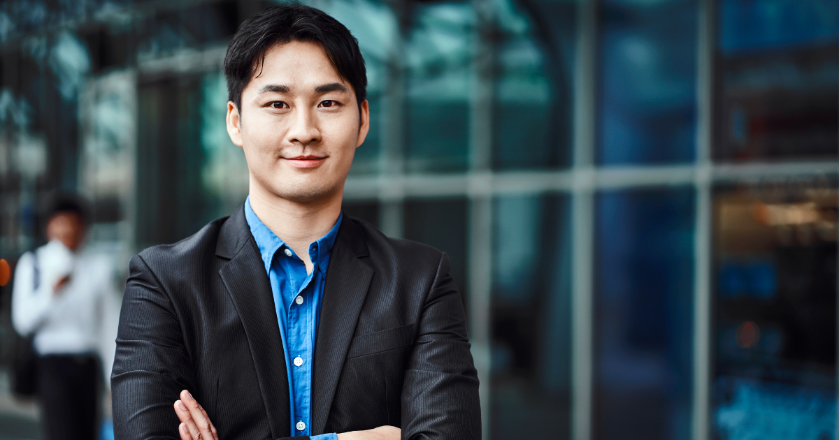 腕を組んで正面を見つめるスーツ姿の男性