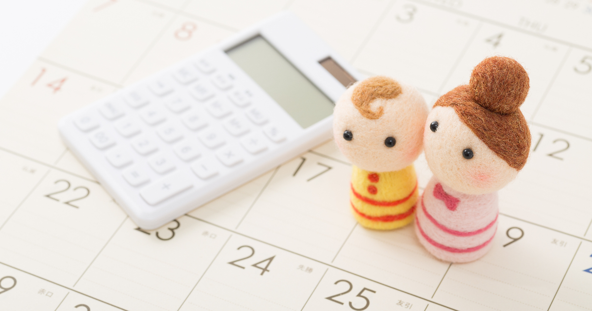 カレンダーの上に置かれた電卓と親子の人形