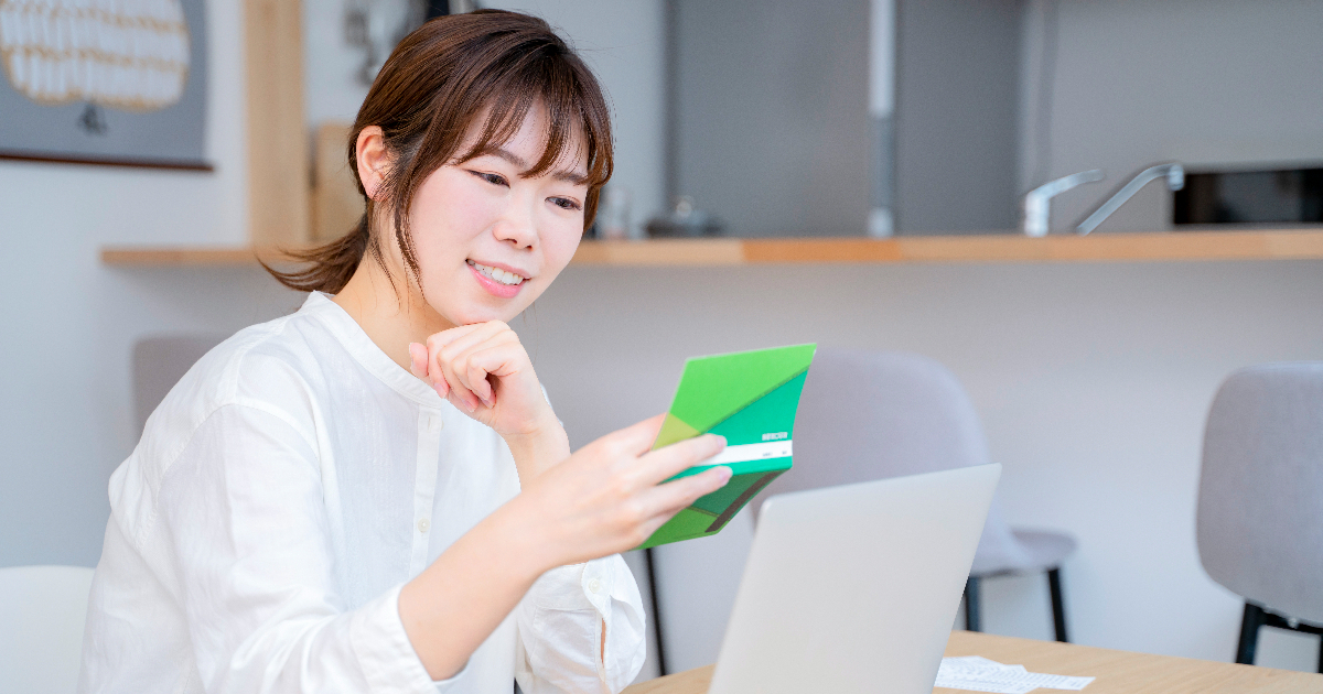 通帳を手に持って考えている女性