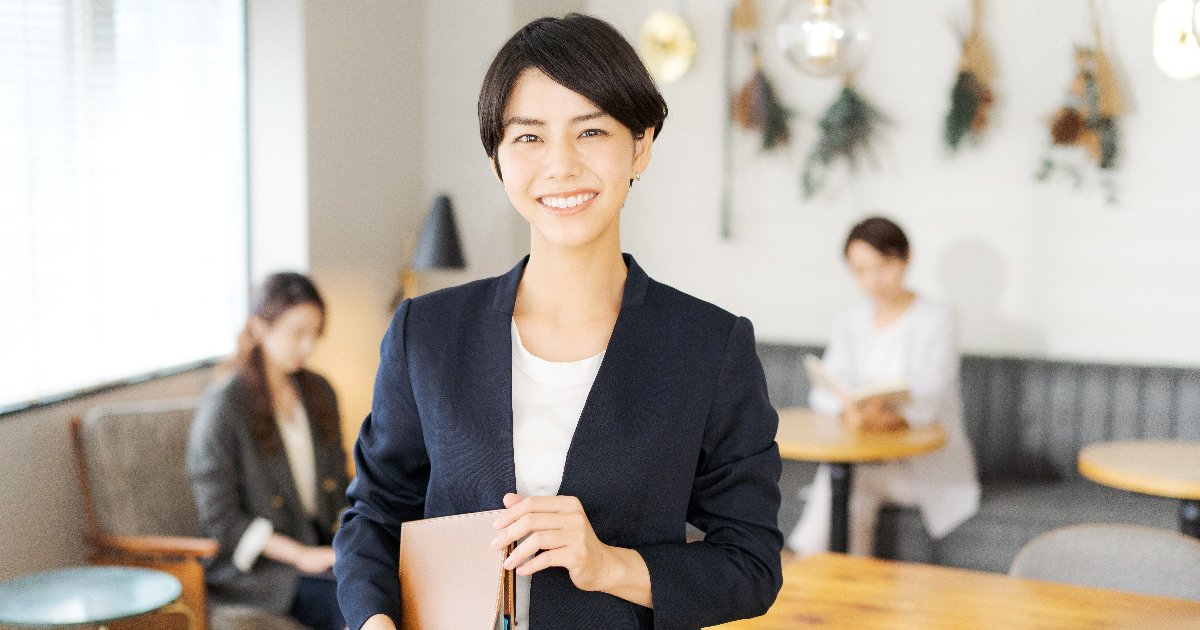 書類を小脇に抱えて笑顔を見せる女性
