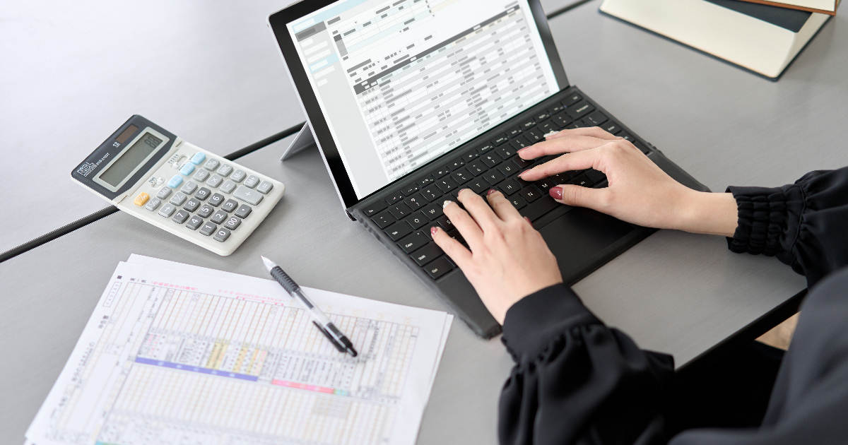 ノートパソコンで帳簿をつける女性