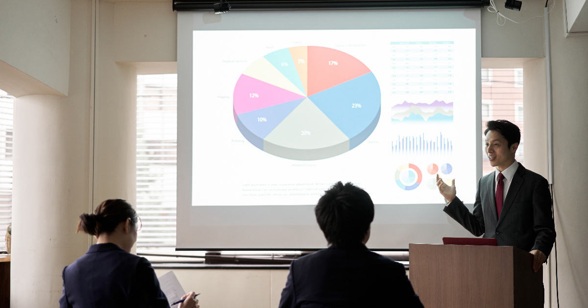 スクリーンに資料を映してプレゼンする男性