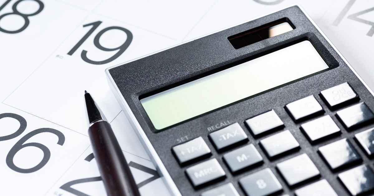 カレンダーの上に置かれた電卓とペン