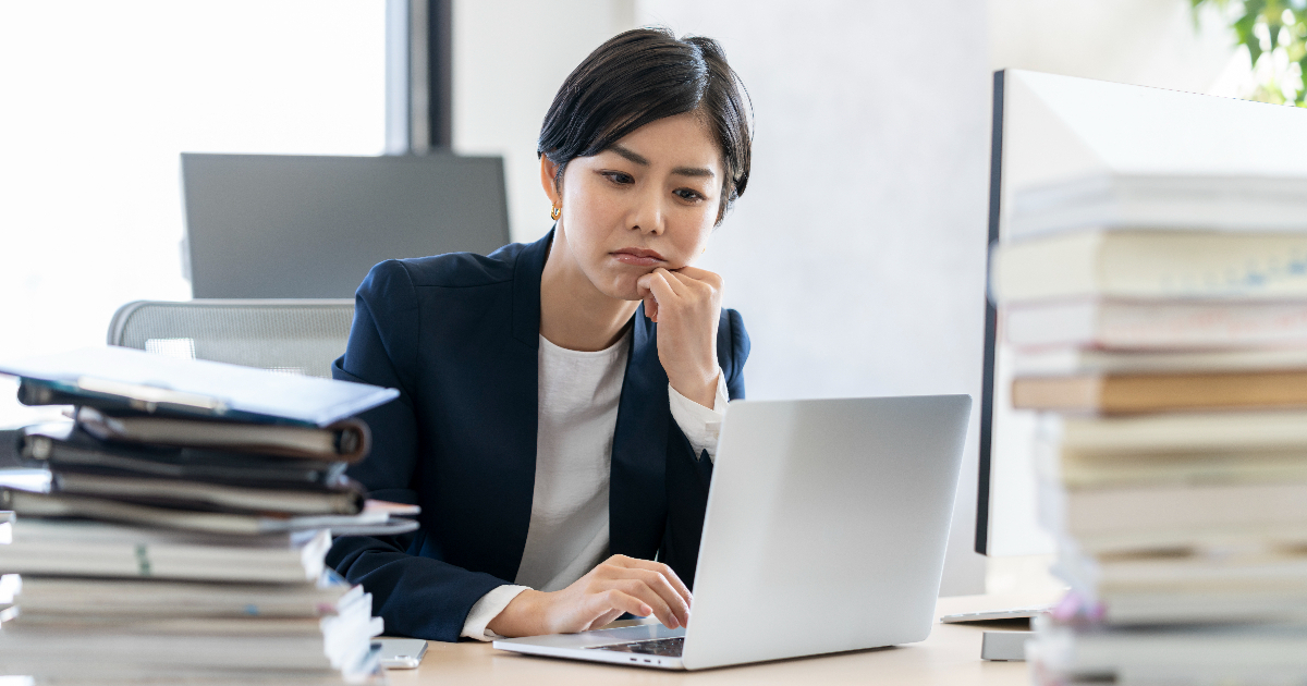 考え事をしながらノートパソコンを操作する女性