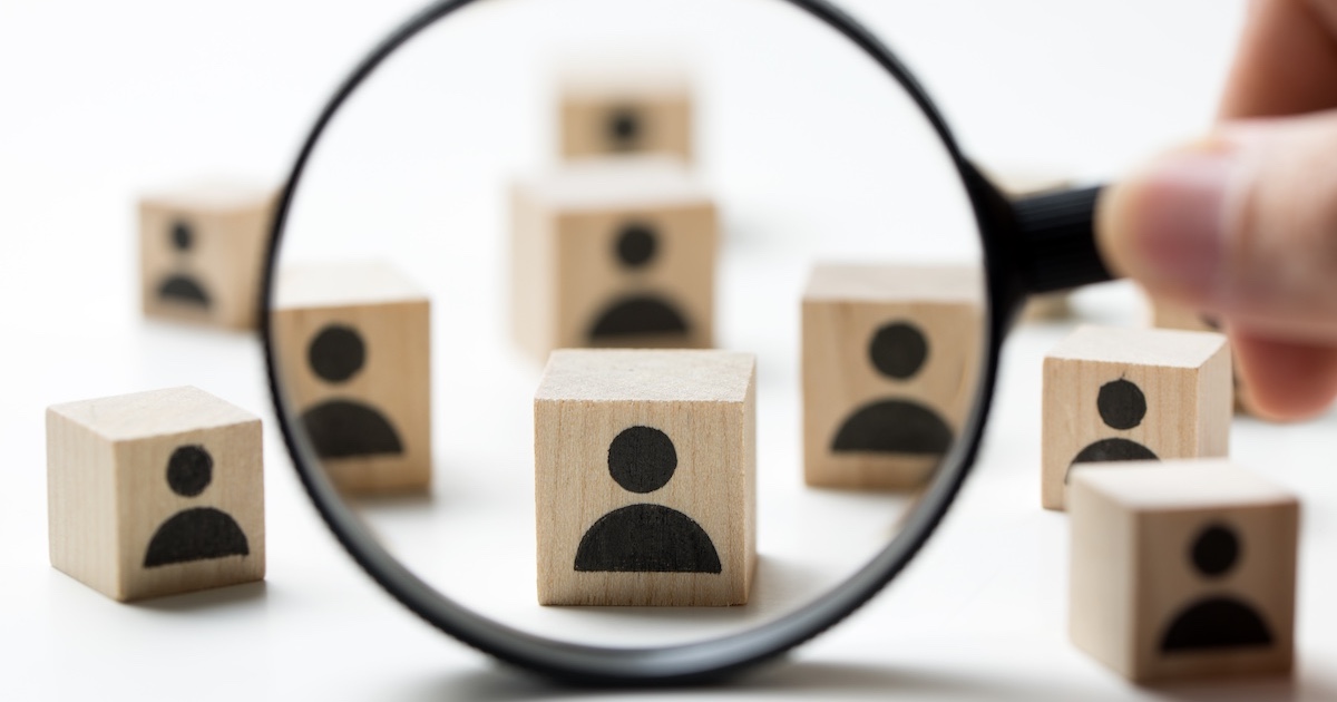 虫眼鏡で人のシルエットが描かれた積木をのぞく