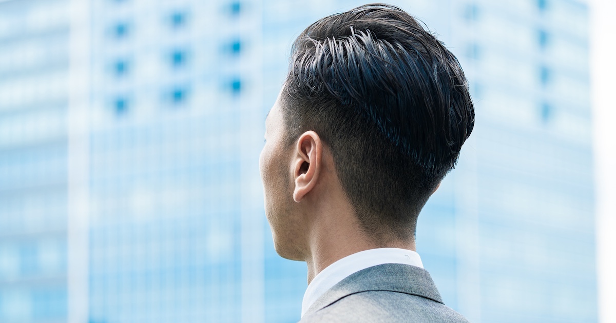 外で向こう側を見つめるビジネスパーソンの後ろ姿