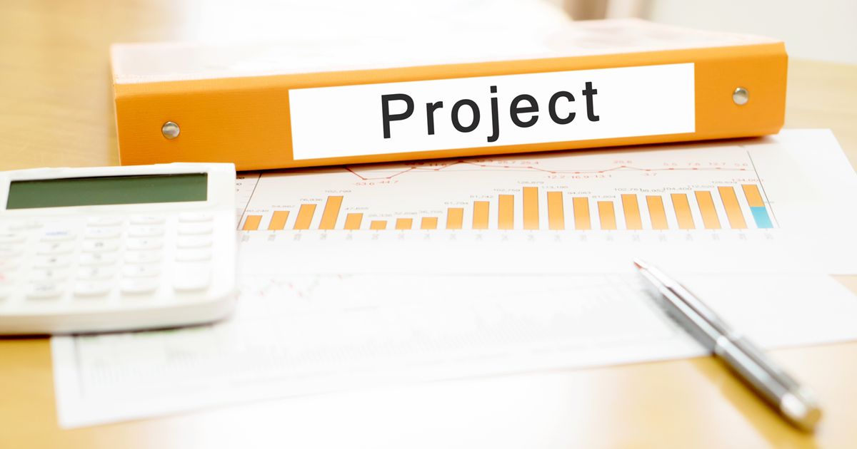 机の上に置かれたファイルと電卓と資料