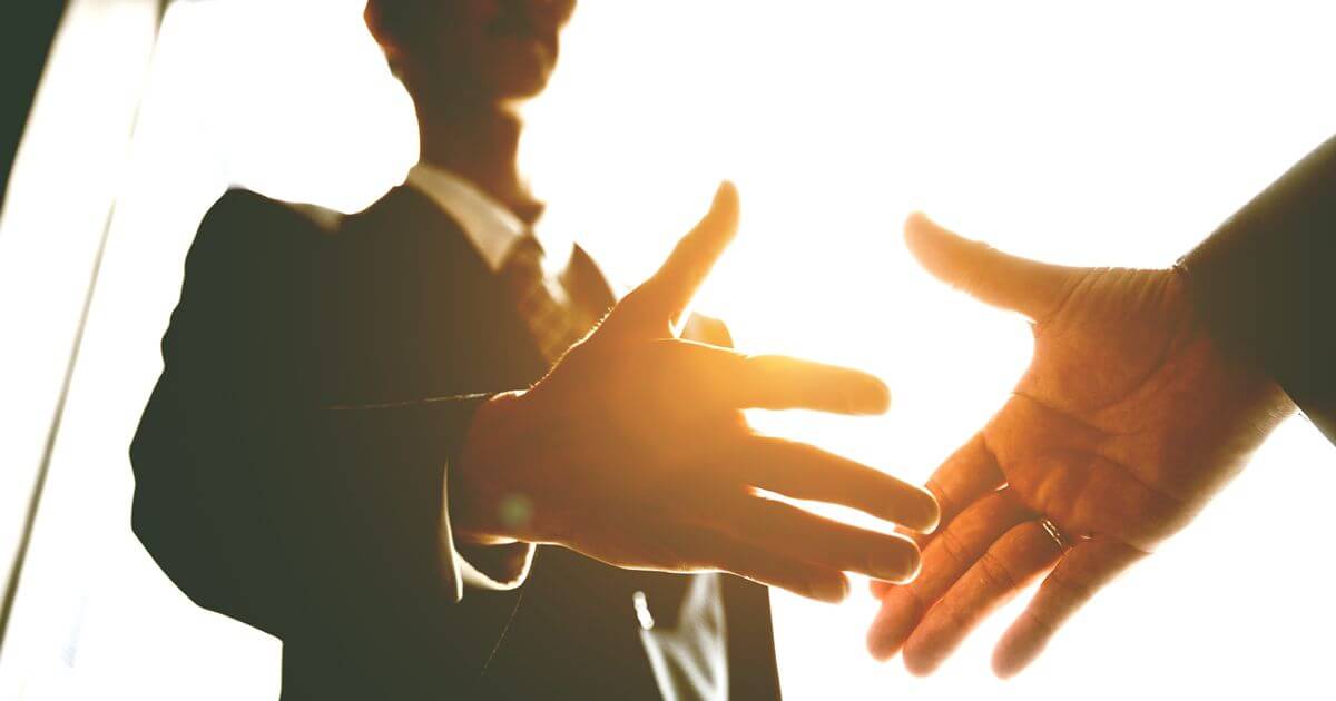 握手をしようとしているスーツの男性