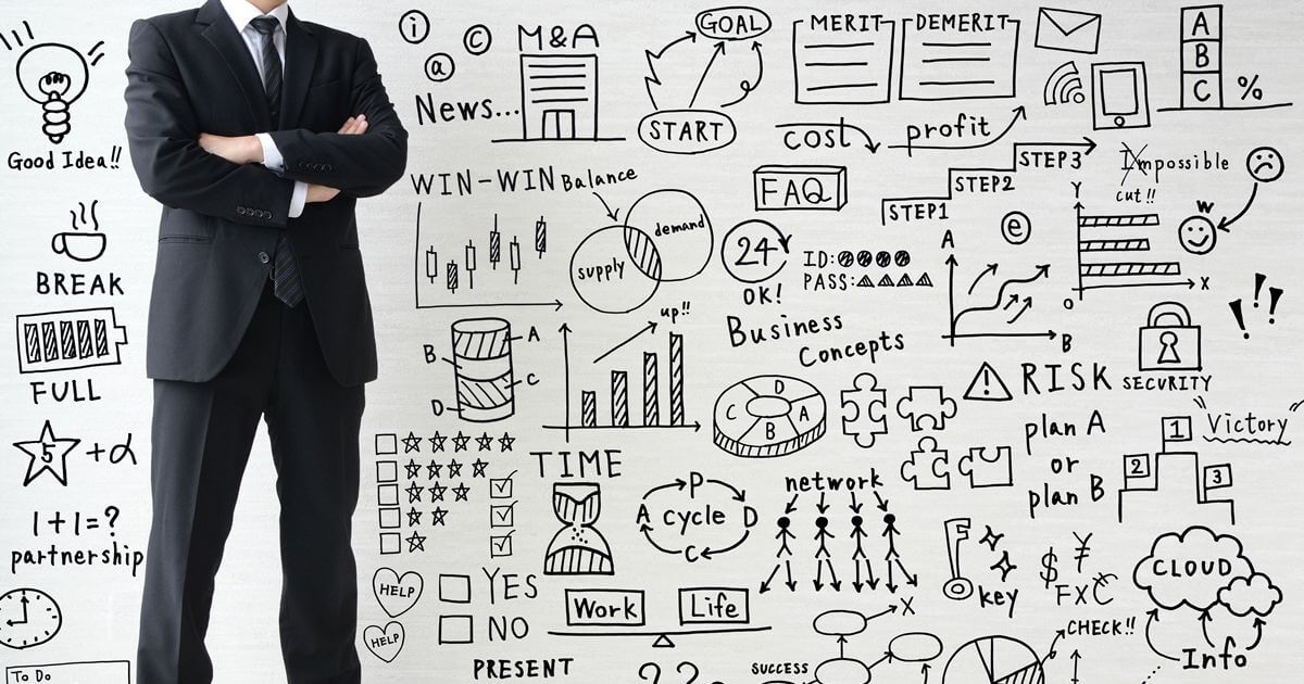 手書きのダイアグラムを背景に腕を組むスーツの男性