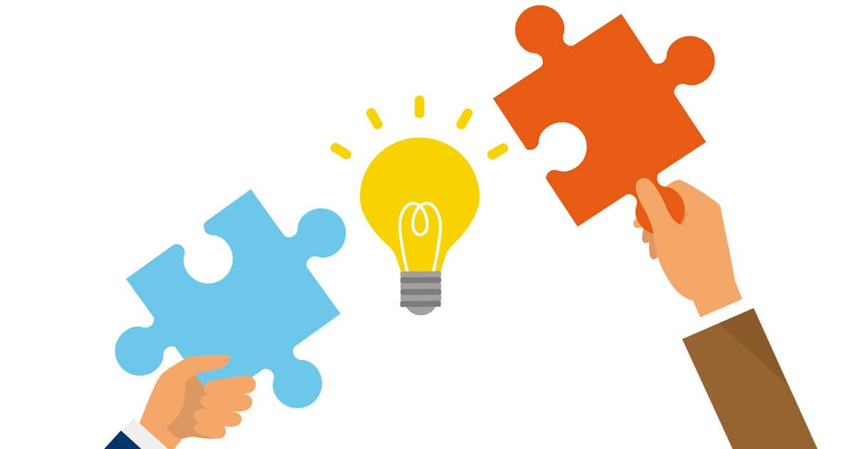 手に持っている2つのパズルピースの間に電球があるイラスト