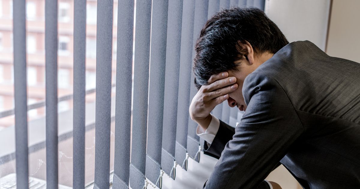 窓際で頭を抱える男性