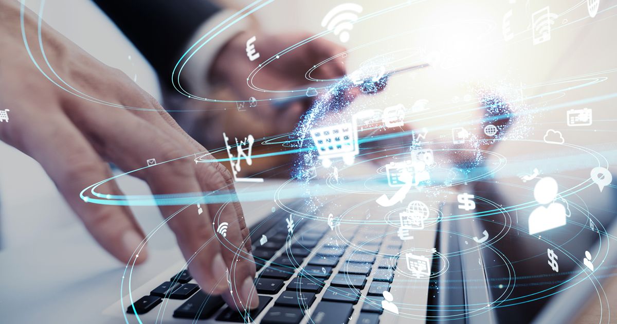 ノートパソコンのキーボードと周辺に広がるデジタル技術のアイコン