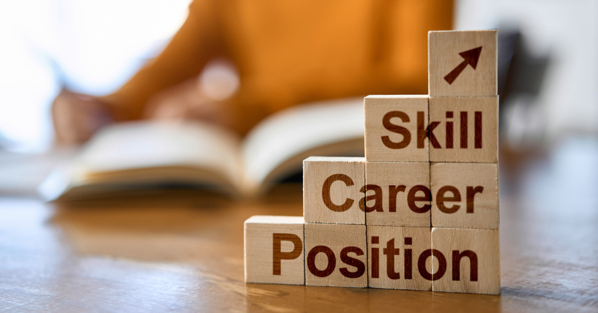 「Position」「Career」「Skill」「矢印」の木製ブロックが積まれている、背景に資格の勉強をする女性