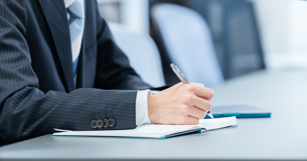 ノートを書くスーツ姿の男性の手元