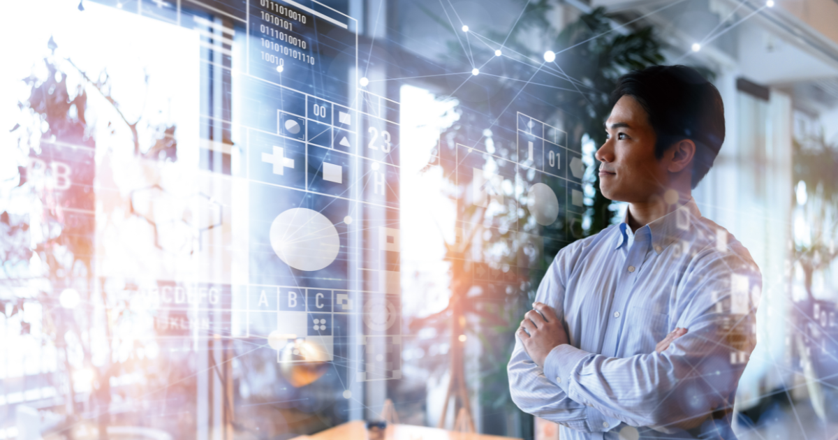 デジタルな情報グラフィックの前で腕を組み、未来を見据えるように立つビジネスパーソン