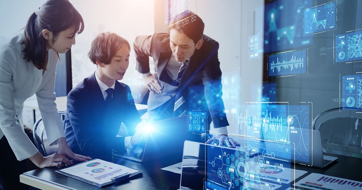 ノートパソコンとホログラムの画面を見ながら会議をするビジネスチーム