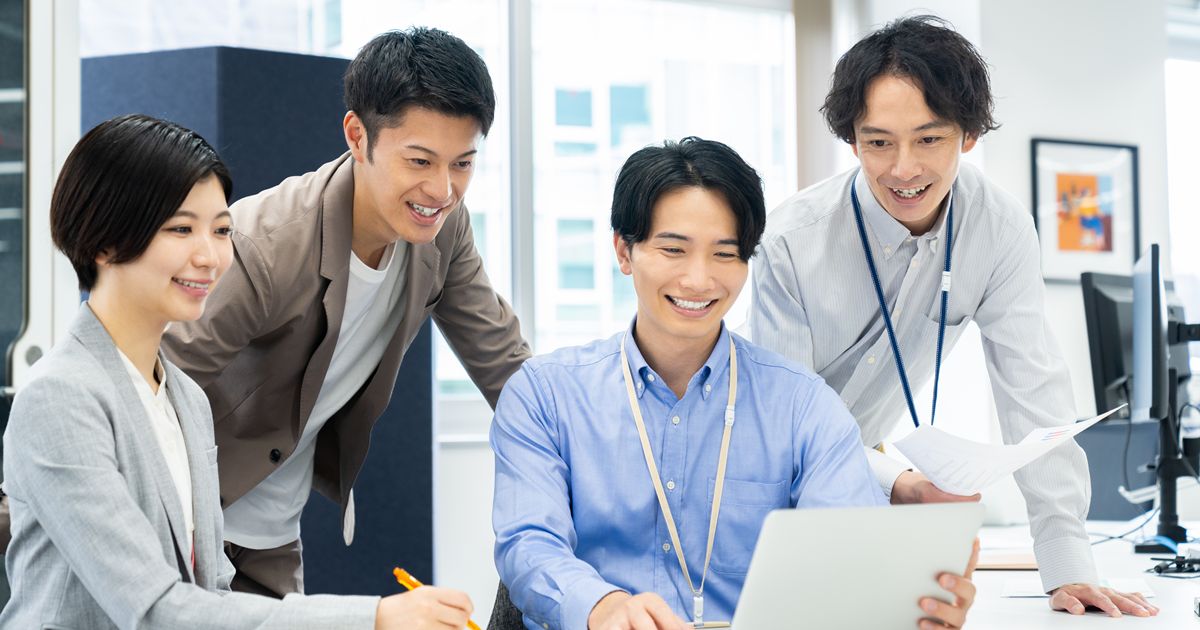 オフィスでラップトップを見ながらアイデアを共有する4人の男女