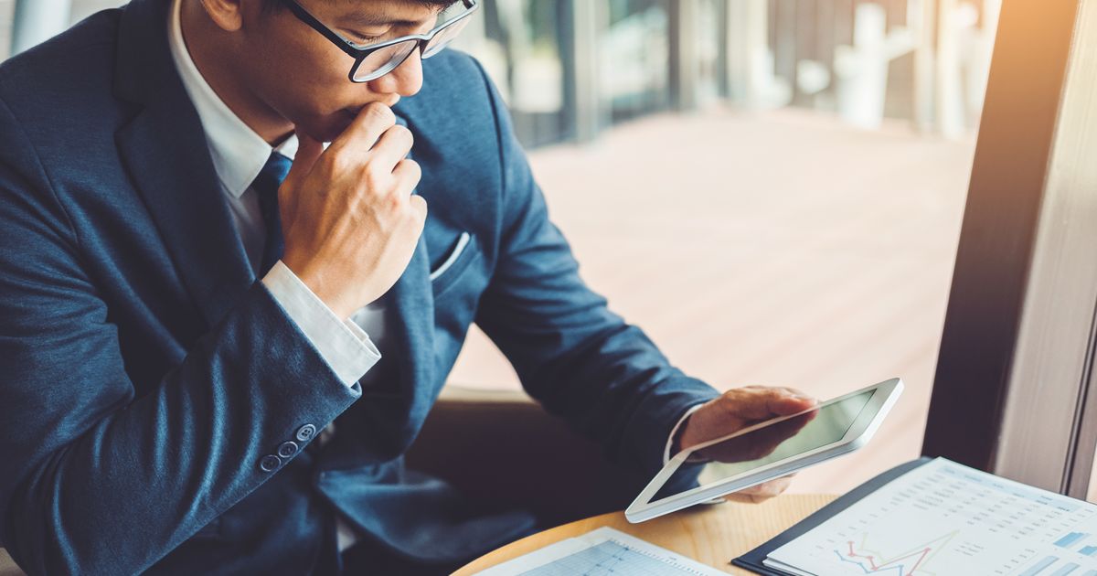 タブレットを見て思案する男性ビジネスパーソン