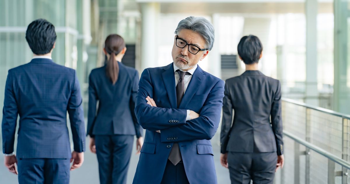 群衆の中で腕を組み、不満げな表情のシニアビジネスマン