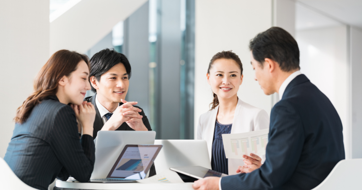 ミーティング中の4人の社員、円満な様子、パソコンを置いている