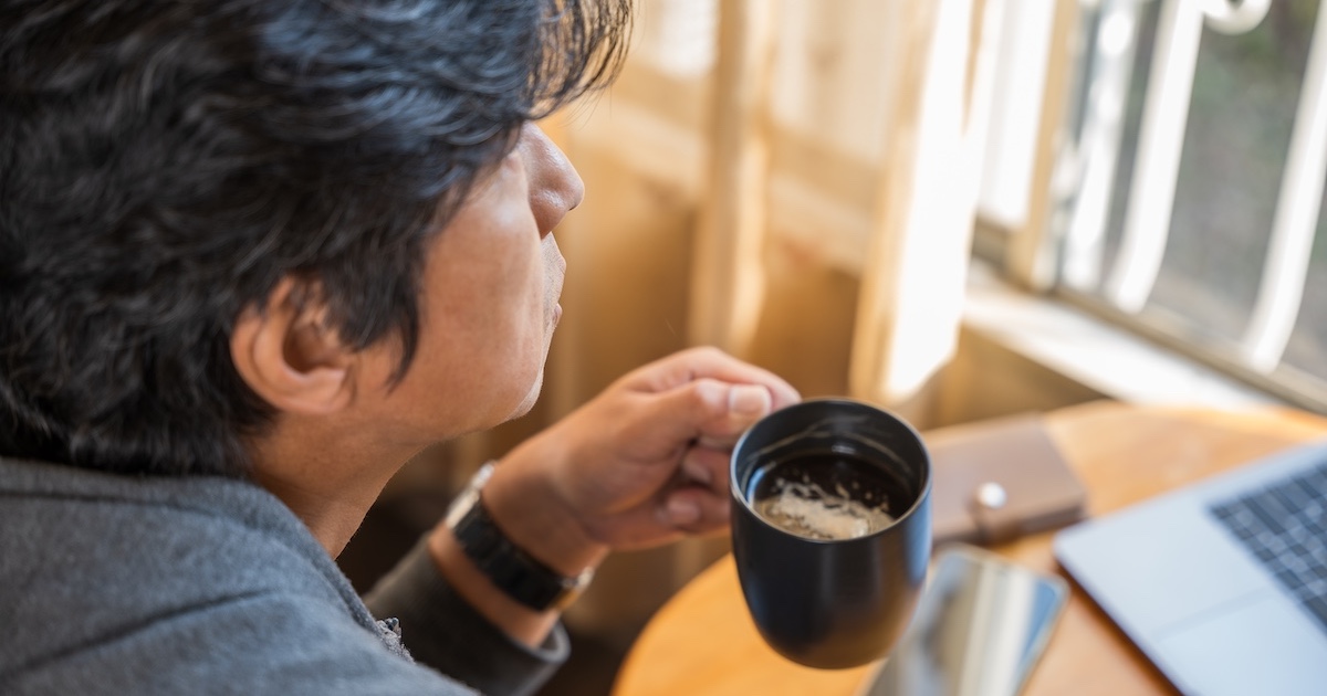 コーヒーを手に考える男性