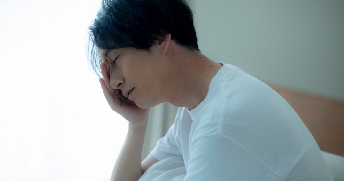 ベッドで疲れて寝不足な様子の男性