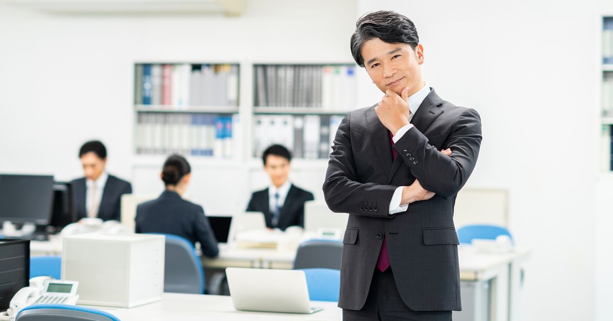 オフィスで腕を組んでポーズをとるスーツ姿の男性