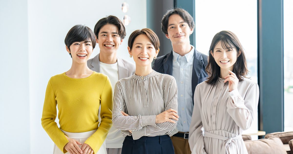 オフィスで笑顔を見せるカジュアルな服装の男女5人