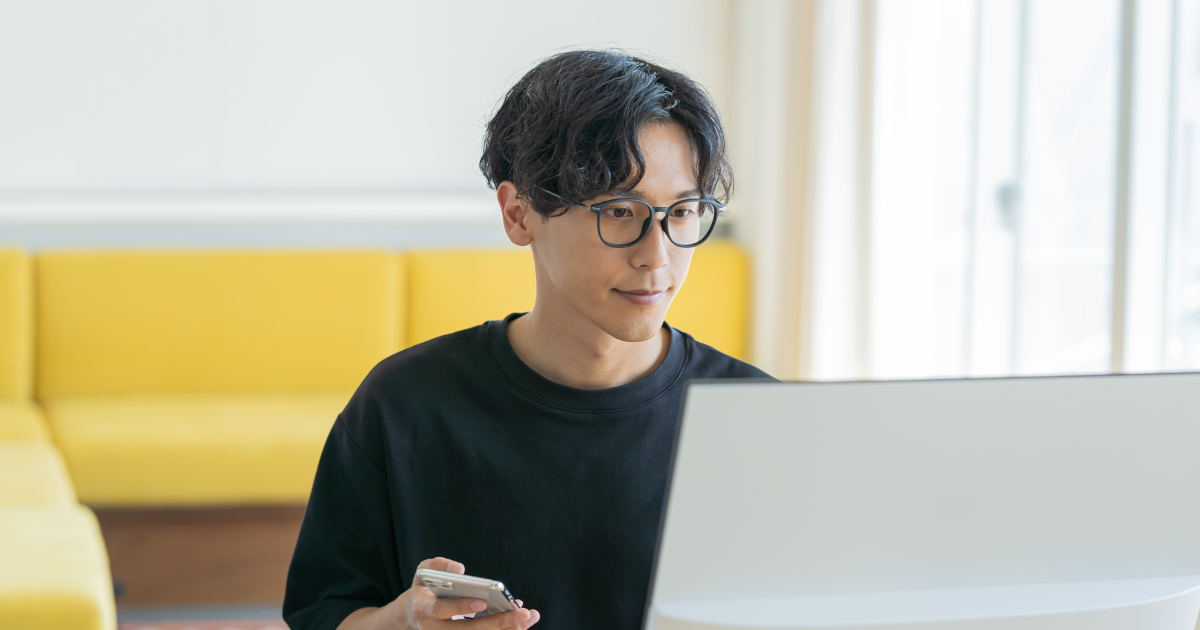 ノートPCとスマホを使い仕事に集中している男性